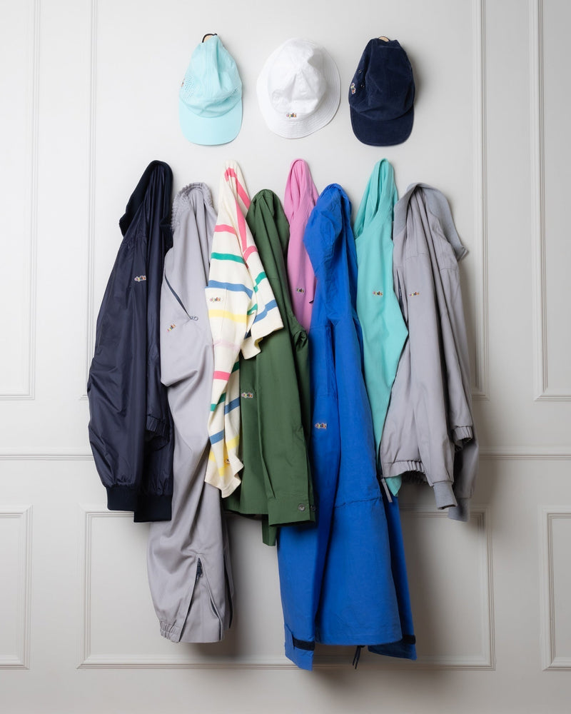 Silver Raven jackets, tops and caps in assorted colours hanging on hooks against a white panelled wall.